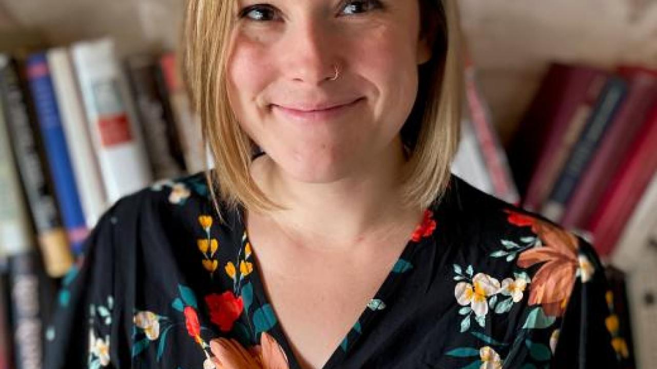 A woman wearing a floral top standing in front of books