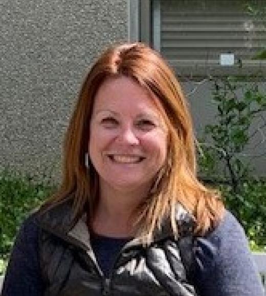 A photo of a woman standing outside, facing the camera and smiling.