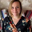 A woman wearing a floral top standing in front of books