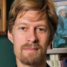 Man with goatee in front of a bookcase