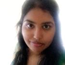 Portrait photograph of a young woman with long dark hair, green embroidered top, slight smile